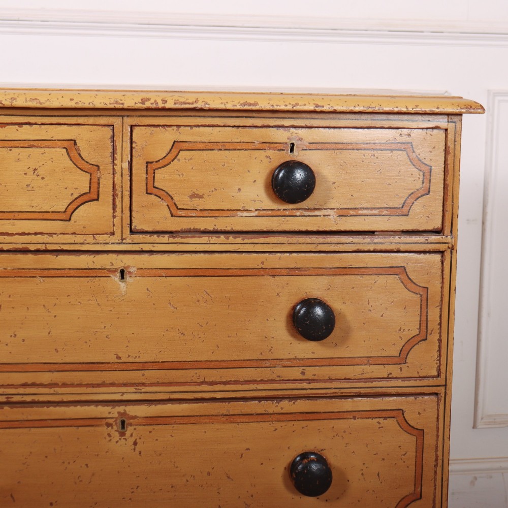 An antique yellow painted pine chest of drawers with two small drawers over three full-width drawers, featuring dark line border detailing, timber knobs, and turned feet. View III