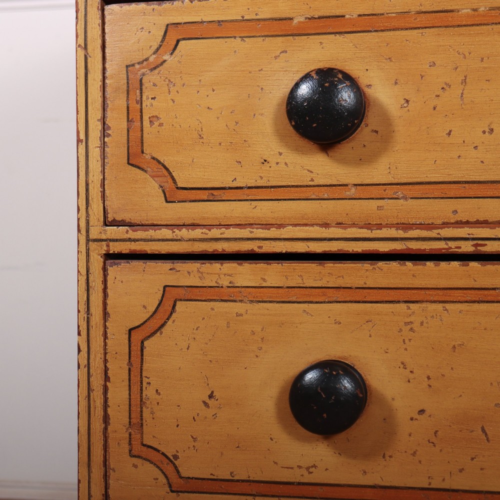 An antique yellow painted pine chest of drawers with two small drawers over three full-width drawers, featuring dark line border detailing, timber knobs, and turned feet. View VI
