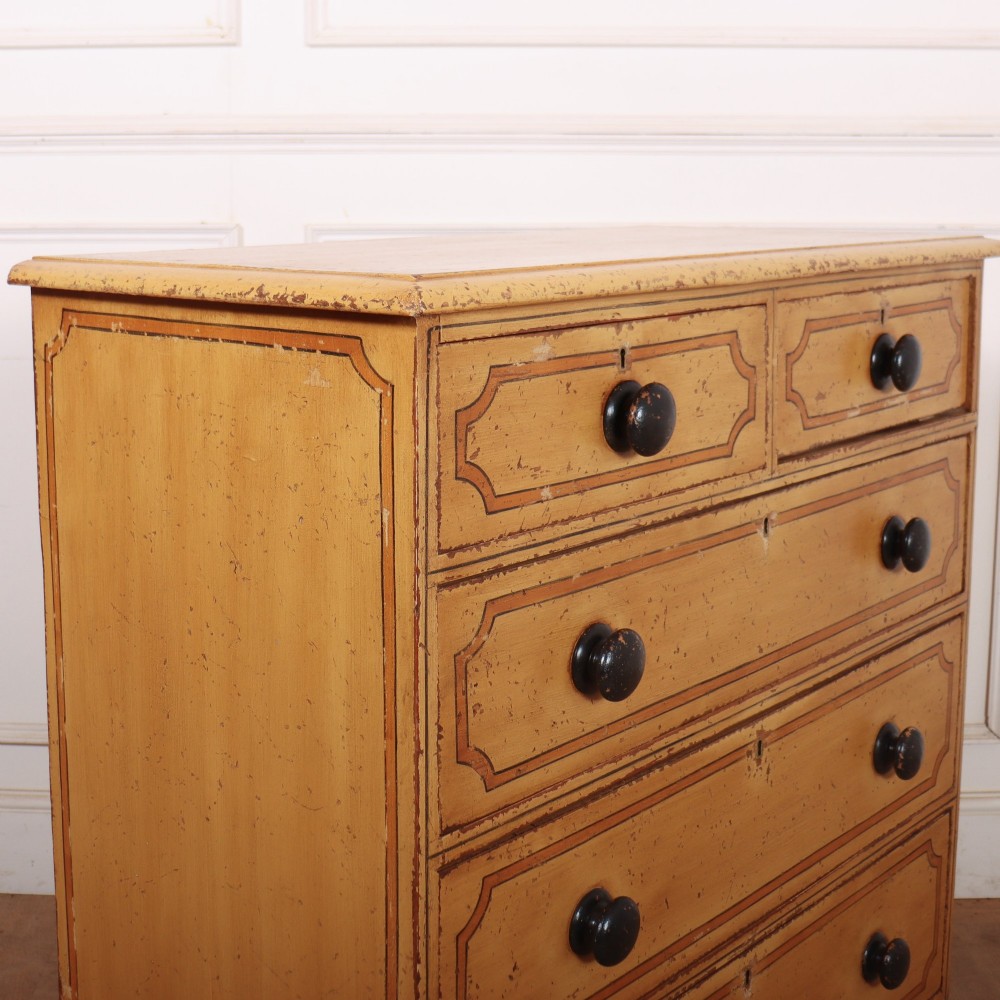 An antique yellow painted pine chest of drawers with two small drawers over three full-width drawers, featuring dark line border detailing, timber knobs, and turned feet. View IX