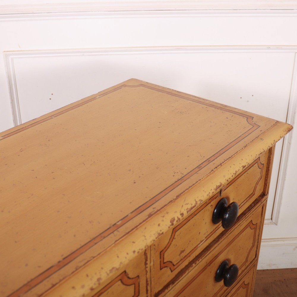 An antique yellow painted pine chest of drawers with two small drawers over three full-width drawers, featuring dark line border detailing, timber knobs, and turned feet. View XI