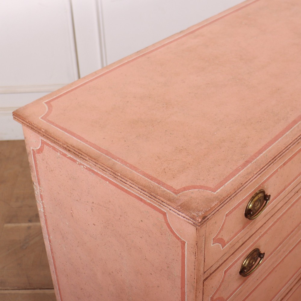 An antique English four-drawer chest featuring a muted pink painted finish with contrasting painted frame borders and brass oval handles on bracket feet. View XI