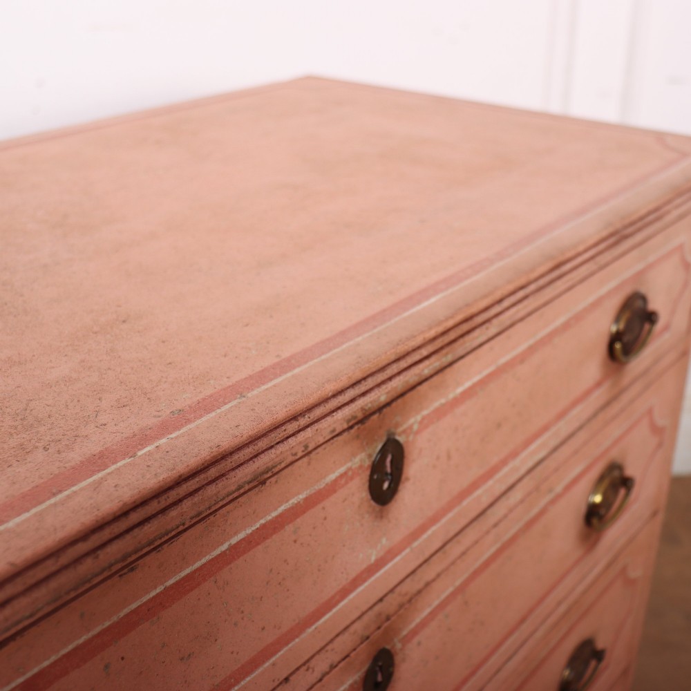 An antique English four-drawer chest featuring a muted pink painted finish with contrasting painted frame borders and brass oval handles on bracket feet. View XIII