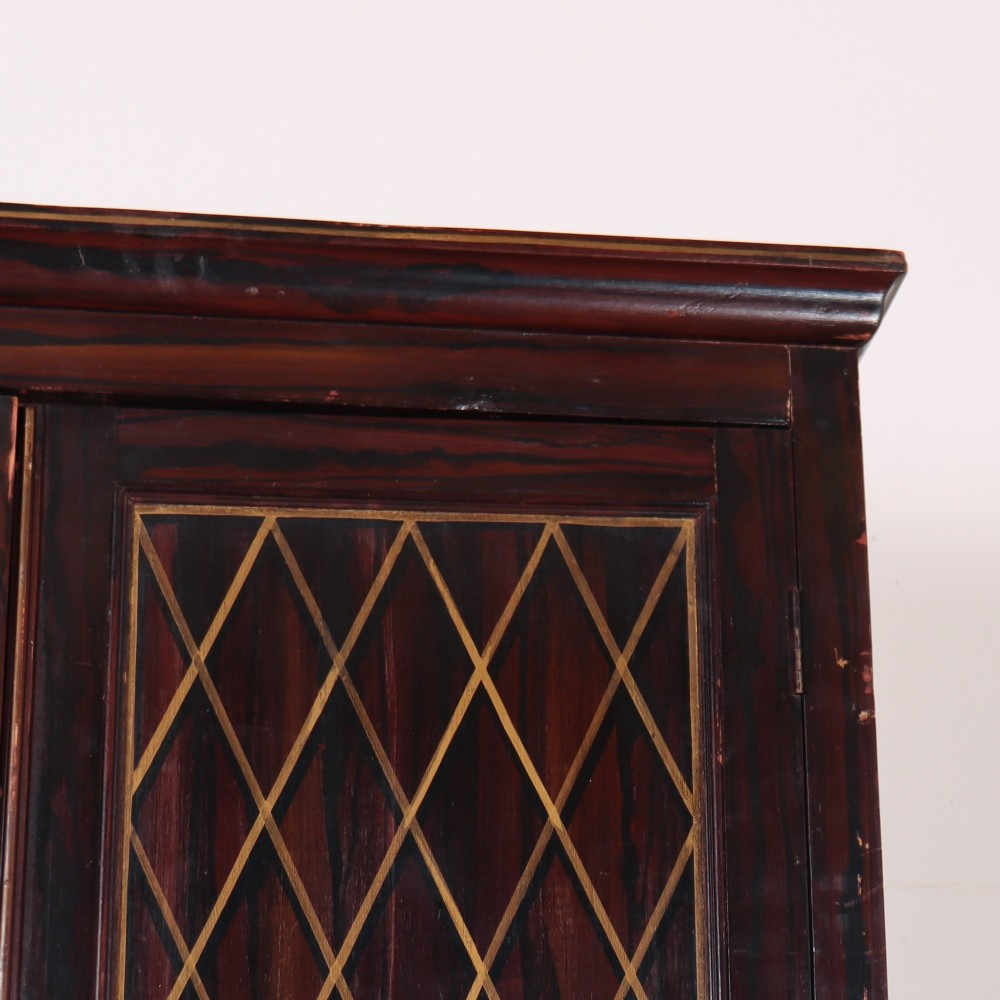 A tall 19th-century dark painted wooden cupboard with two tiers of double doors decorated with gold painted diamond lattice panels. View III
