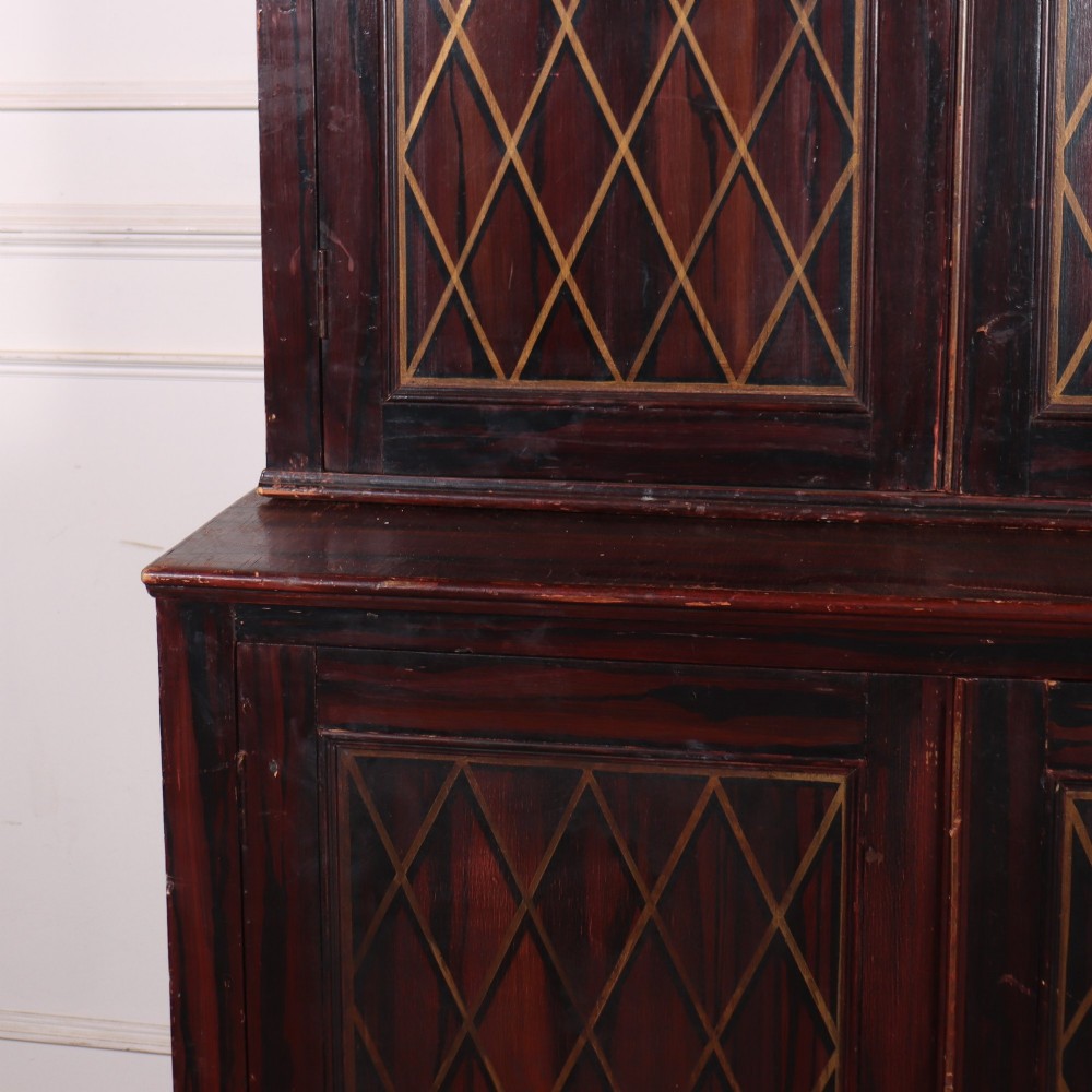 A tall 19th-century dark painted wooden cupboard with two tiers of double doors decorated with gold painted diamond lattice panels. View V