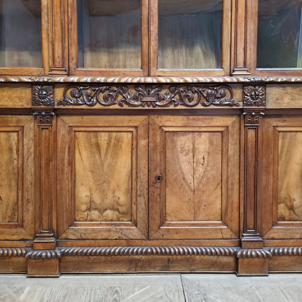 A large French walnut bookcase featuring six glazed upper doors above six panelled lower cupboard doors with carved scrollwork along the upper frieze. View III