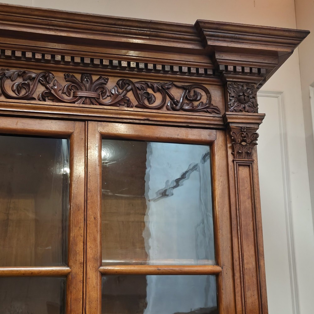 A large French walnut bookcase featuring six glazed upper doors above six panelled lower cupboard doors with carved scrollwork along the upper frieze. View VII