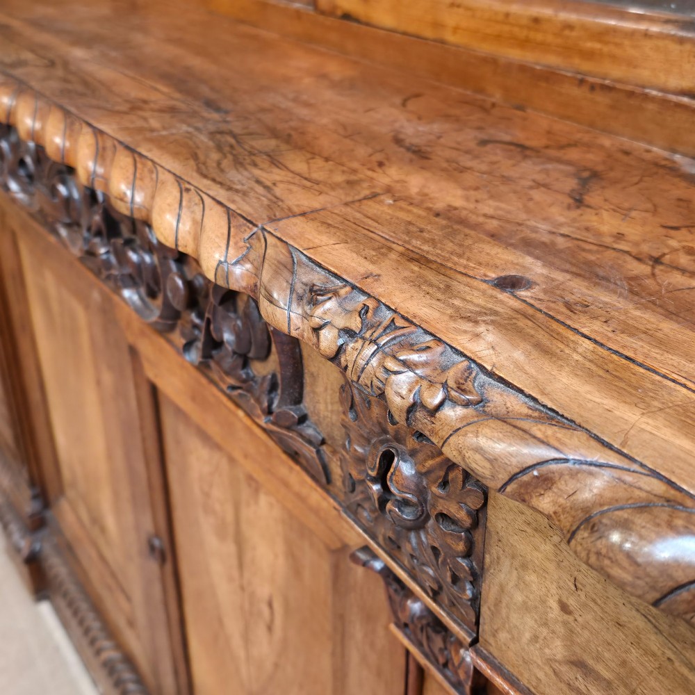 A large French walnut bookcase featuring six glazed upper doors above six panelled lower cupboard doors with carved scrollwork along the upper frieze. View IX