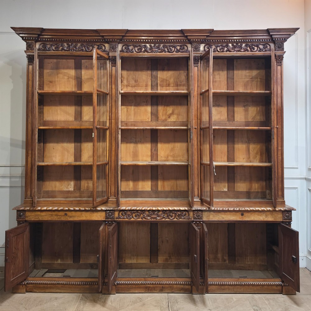 A large French walnut bookcase featuring six glazed upper doors above six panelled lower cupboard doors with carved scrollwork along the upper frieze. View XIII