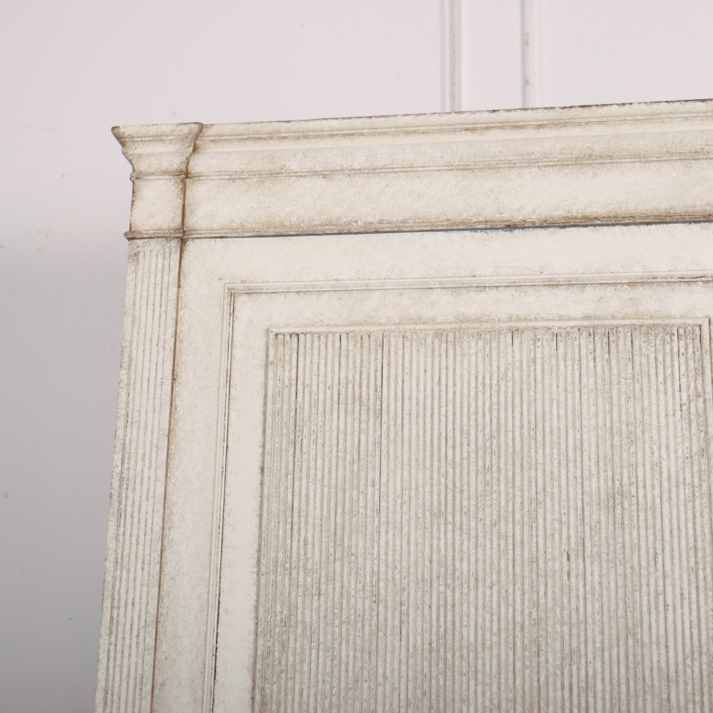 A tall off-white painted Scandinavian style linen cupboard featuring a two-door upper section above three drawers with circular brass handles. View II