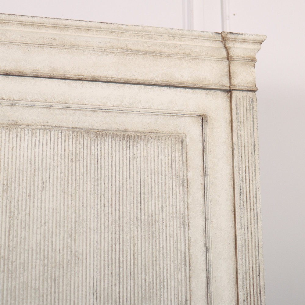 A tall off-white painted Scandinavian style linen cupboard featuring a two-door upper section above three drawers with circular brass handles. View III