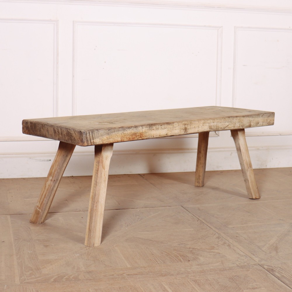 A low rectangular wooden coffee table crafted from thick timber with four splayed legs.