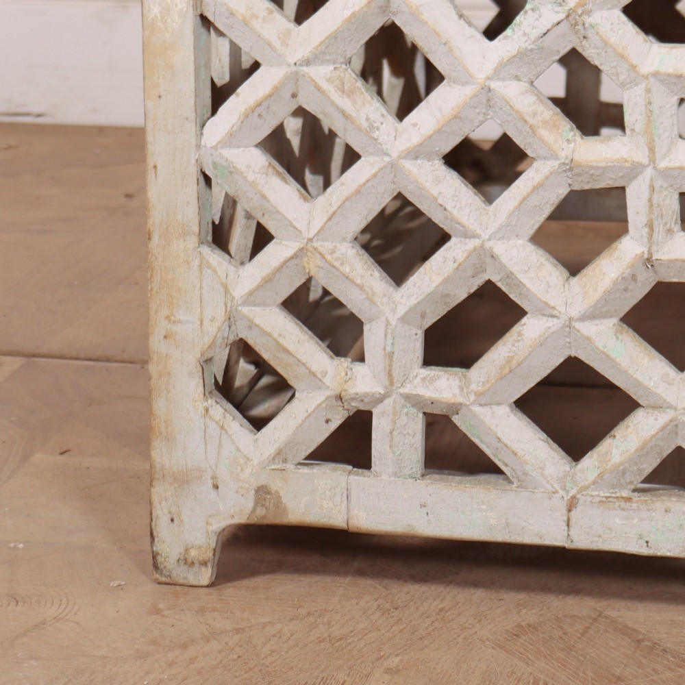 A low rectangular coffee table featuring a plain natural wood top supported by a whitewashed base with geometric lattice fretwork. View III