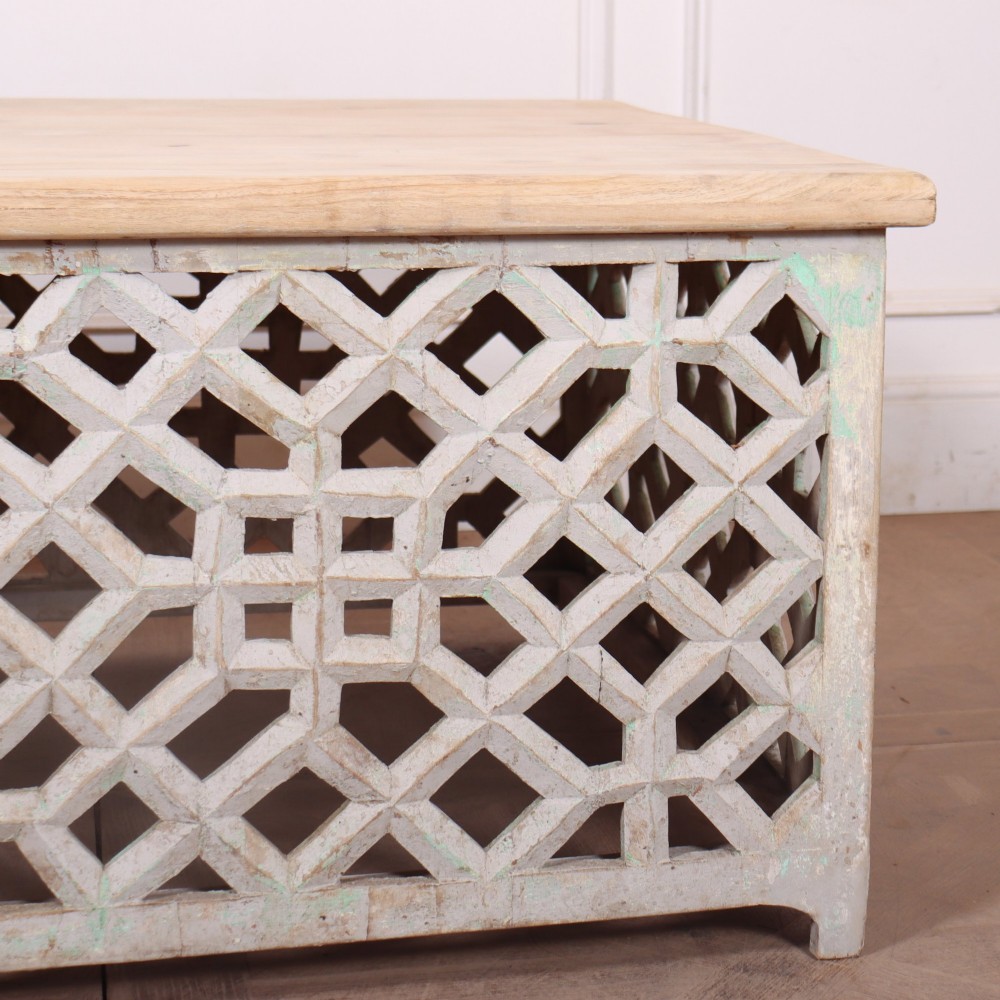 A low rectangular coffee table featuring a plain natural wood top supported by a whitewashed base with geometric lattice fretwork. View IV