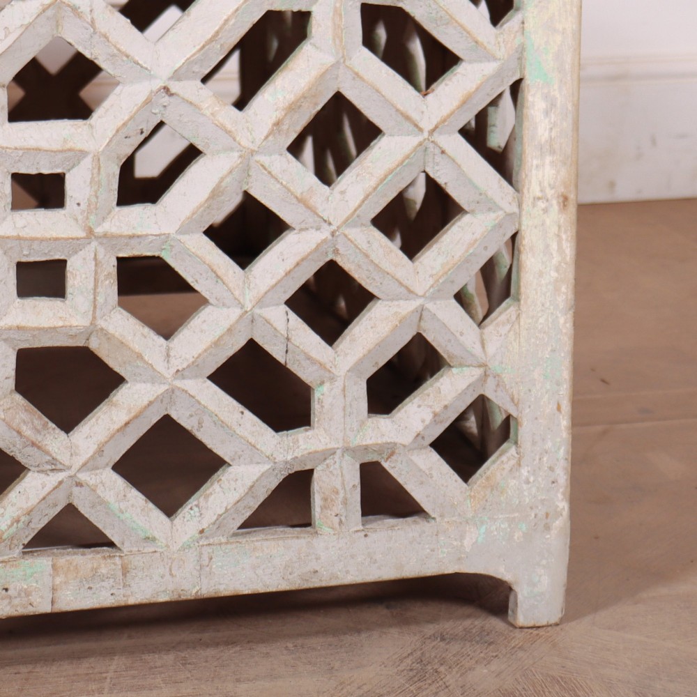 A low rectangular coffee table featuring a plain natural wood top supported by a whitewashed base with geometric lattice fretwork. View V