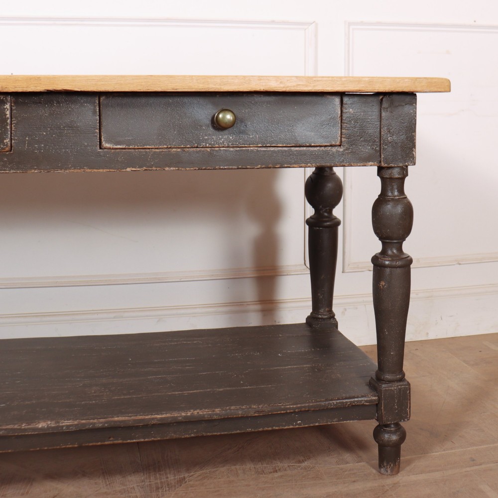 A French drapers table featuring a natural wood top, two shallow drawers with brass knobs, a dark grey painted base, turned legs, and a lower pot board shelf. View IV