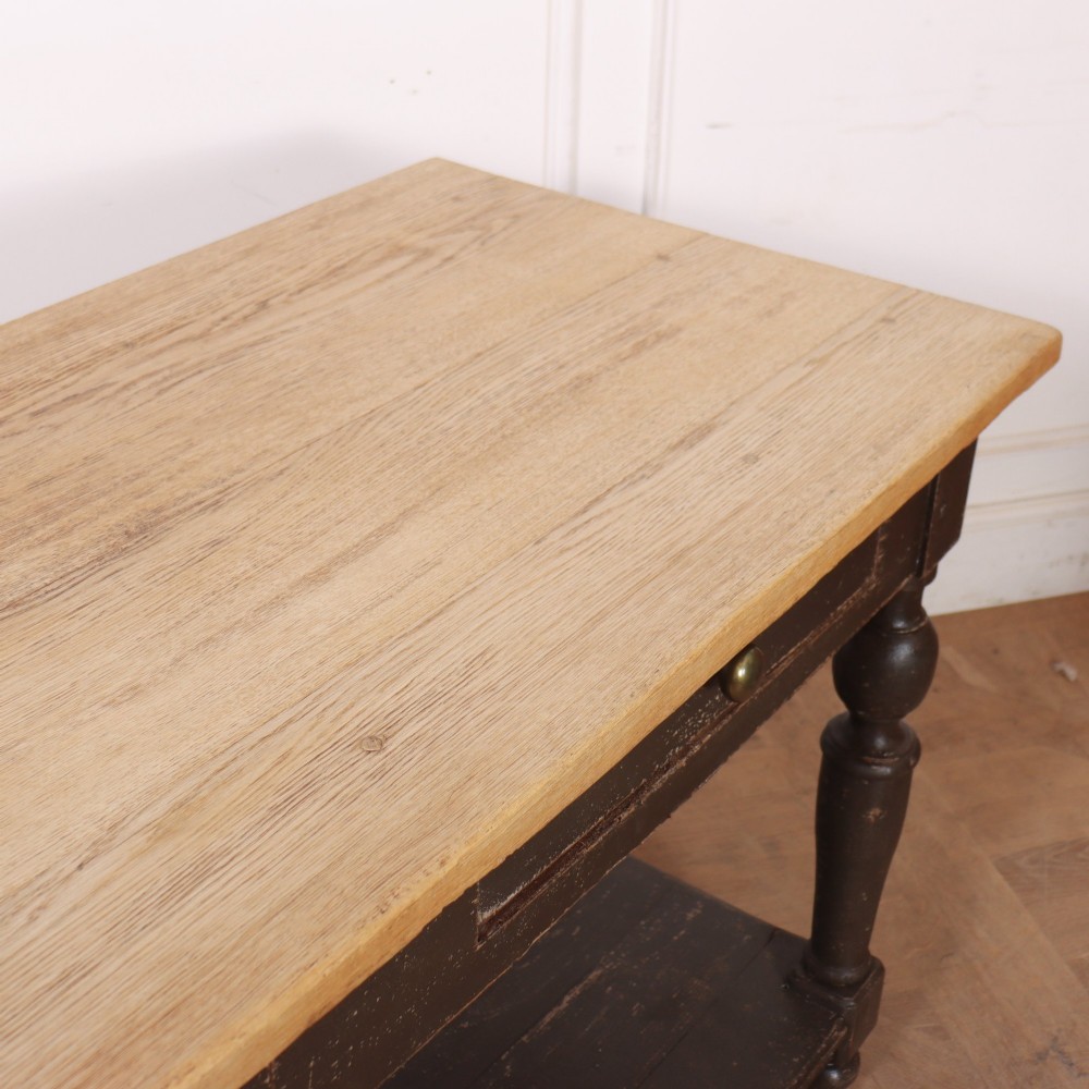 A French drapers table featuring a natural wood top, two shallow drawers with brass knobs, a dark grey painted base, turned legs, and a lower pot board shelf. View IX