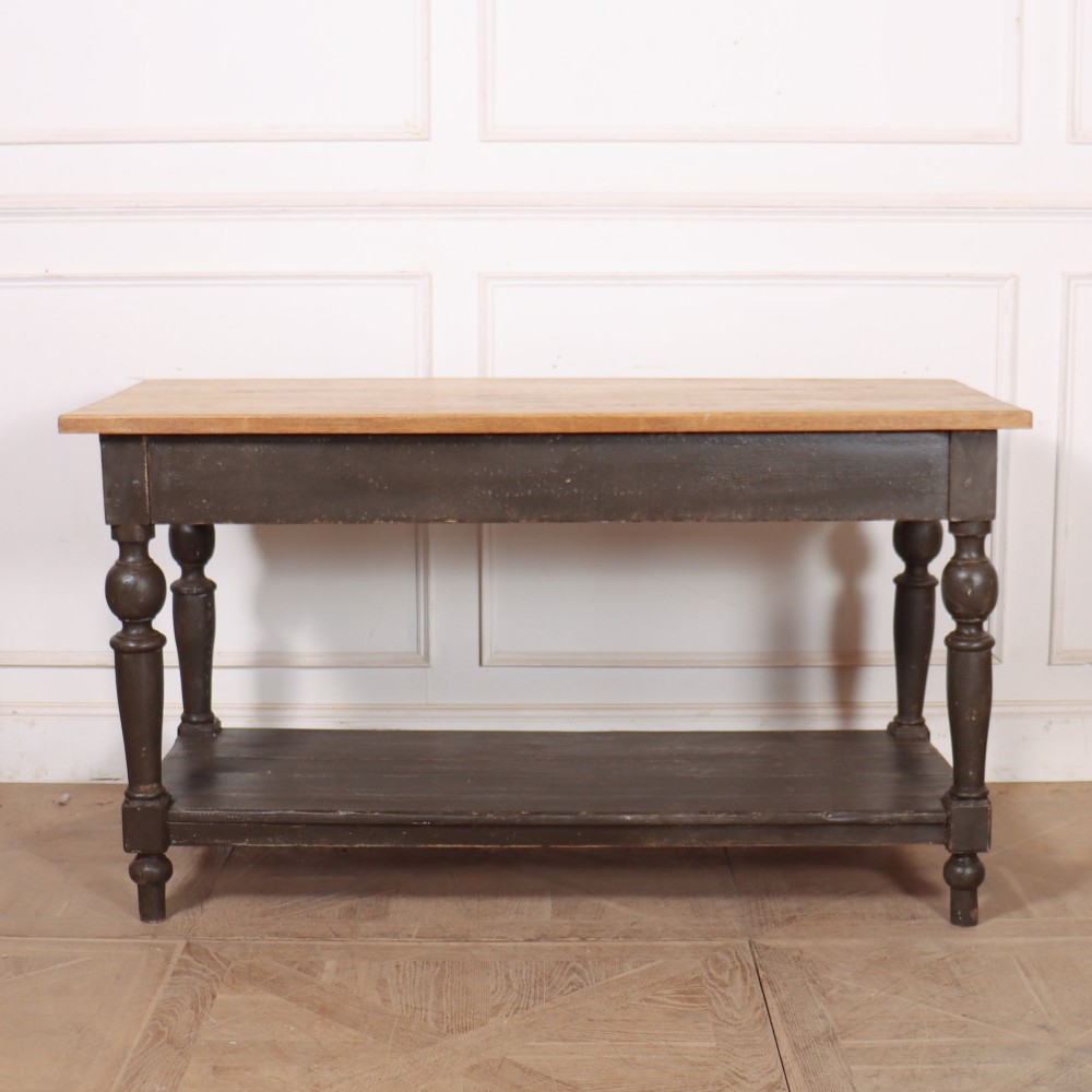 A French drapers table featuring a natural wood top, two shallow drawers with brass knobs, a dark grey painted base, turned legs, and a lower pot board shelf. View XI