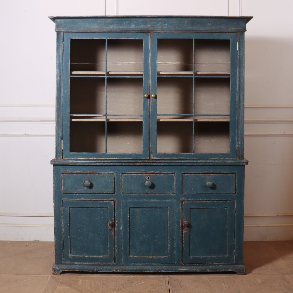 A blue-painted two-part timber dresser featuring an upper section with two glazed six-pane doors and a lower base with three drawers above three panelled cupboard doors.