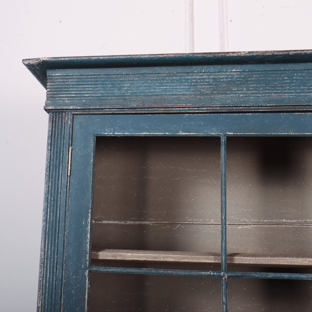A blue-painted two-part timber dresser featuring an upper section with two glazed six-pane doors and a lower base with three drawers above three panelled cupboard doors. View II
