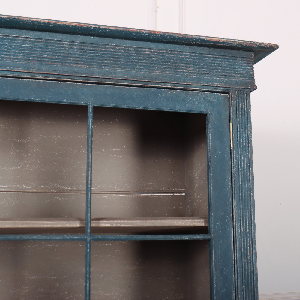 A blue-painted two-part timber dresser featuring an upper section with two glazed six-pane doors and a lower base with three drawers above three panelled cupboard doors. View III