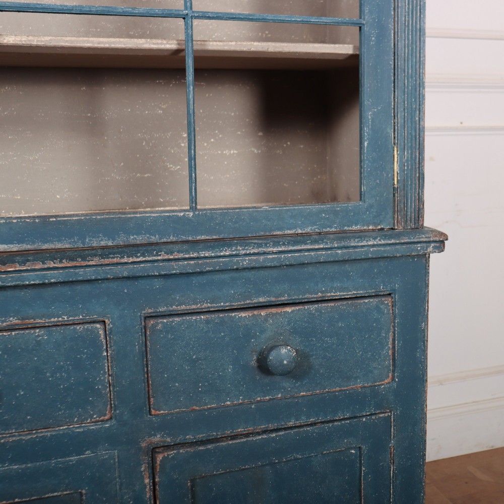 A blue-painted two-part timber dresser featuring an upper section with two glazed six-pane doors and a lower base with three drawers above three panelled cupboard doors. View V