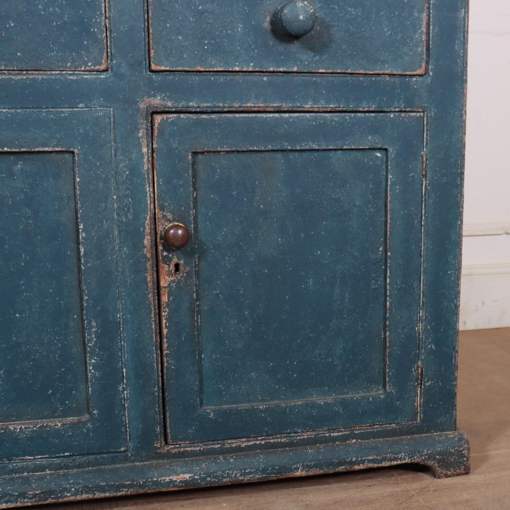 A blue-painted two-part timber dresser featuring an upper section with two glazed six-pane doors and a lower base with three drawers above three panelled cupboard doors. View VII