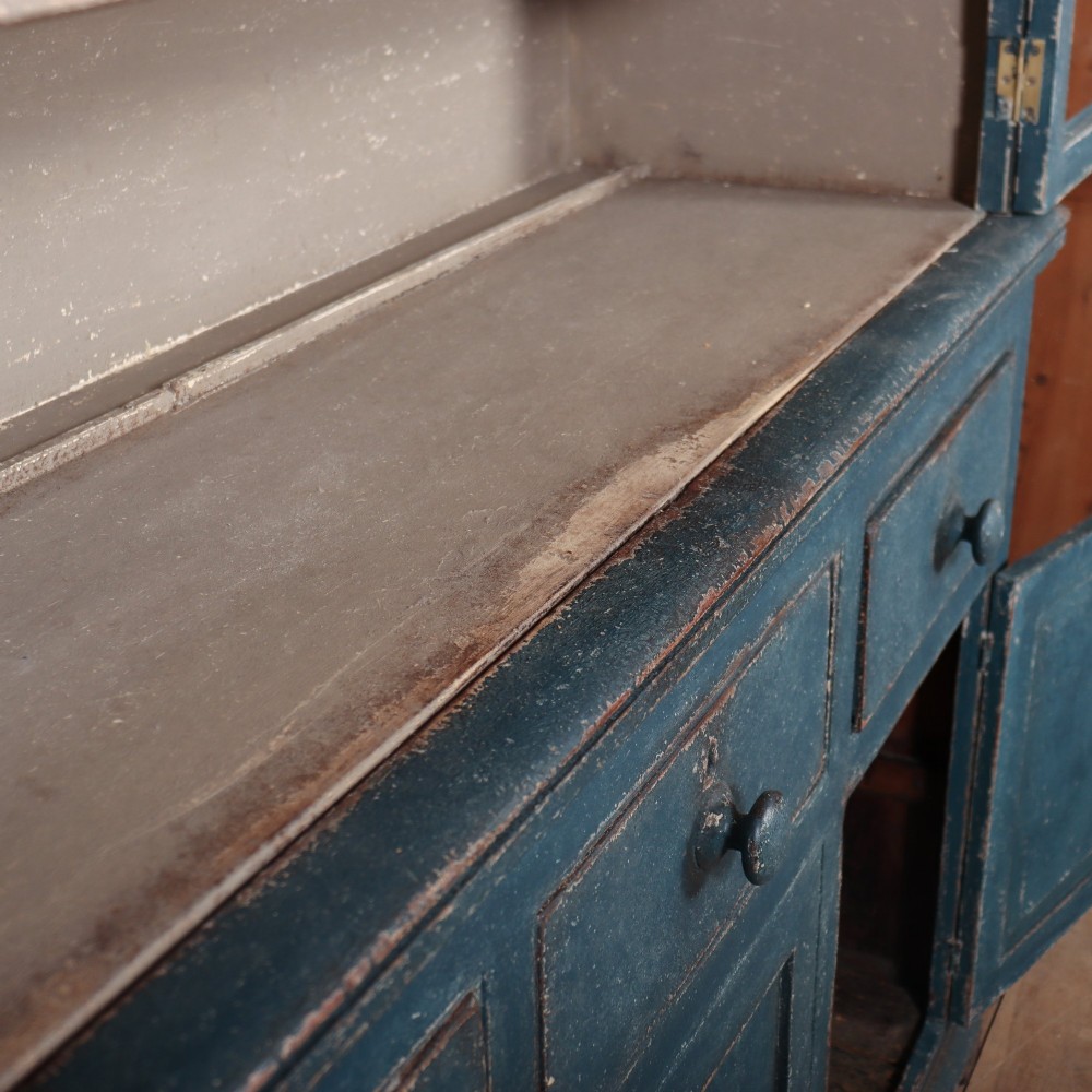 A blue-painted two-part timber dresser featuring an upper section with two glazed six-pane doors and a lower base with three drawers above three panelled cupboard doors. View IX