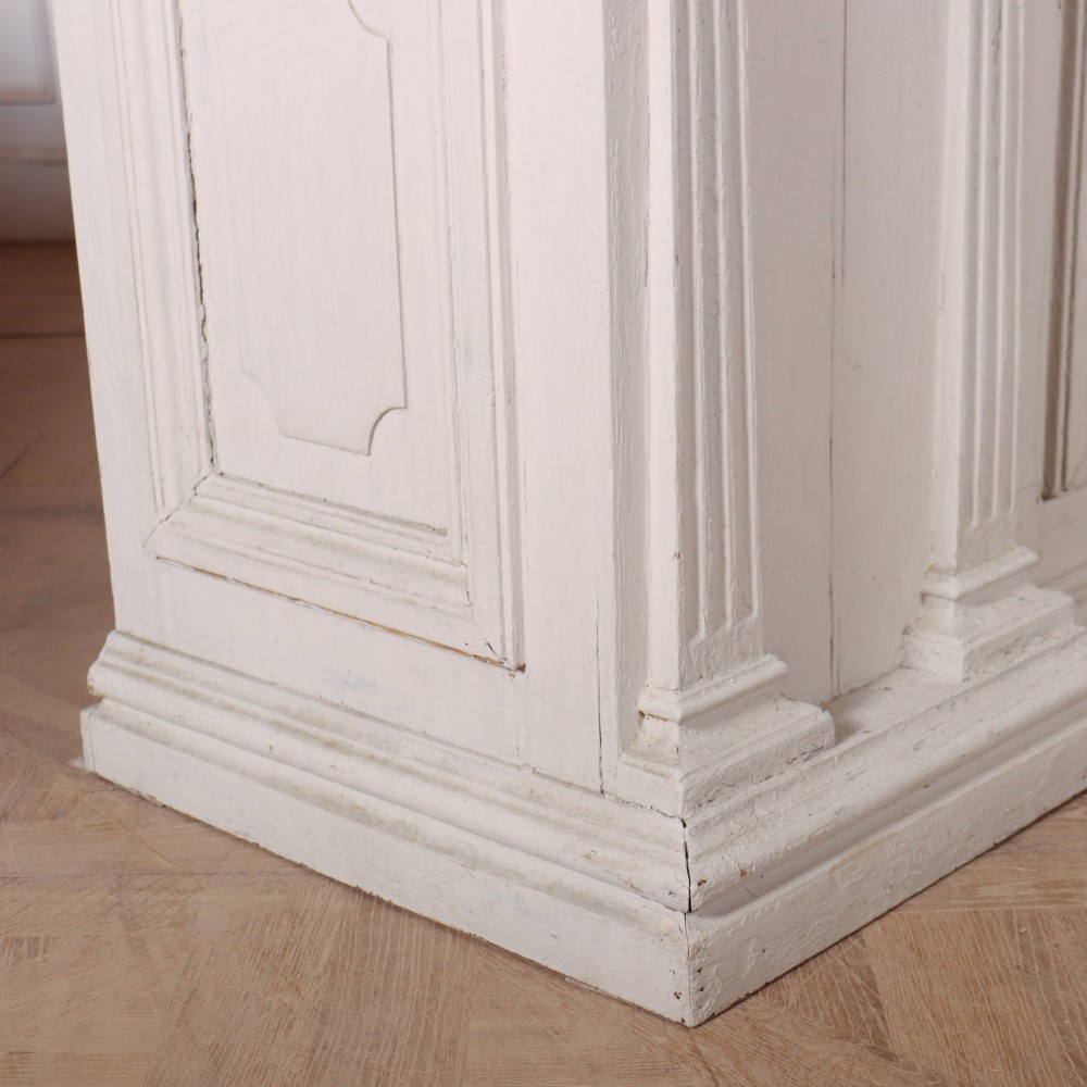 A long off-white painted timber shop counter featuring fluted Corinthian pilasters and recessed panel moulding along the front. View II