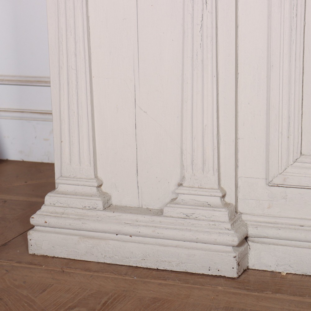 A long off-white painted timber shop counter featuring fluted Corinthian pilasters and recessed panel moulding along the front. View VII