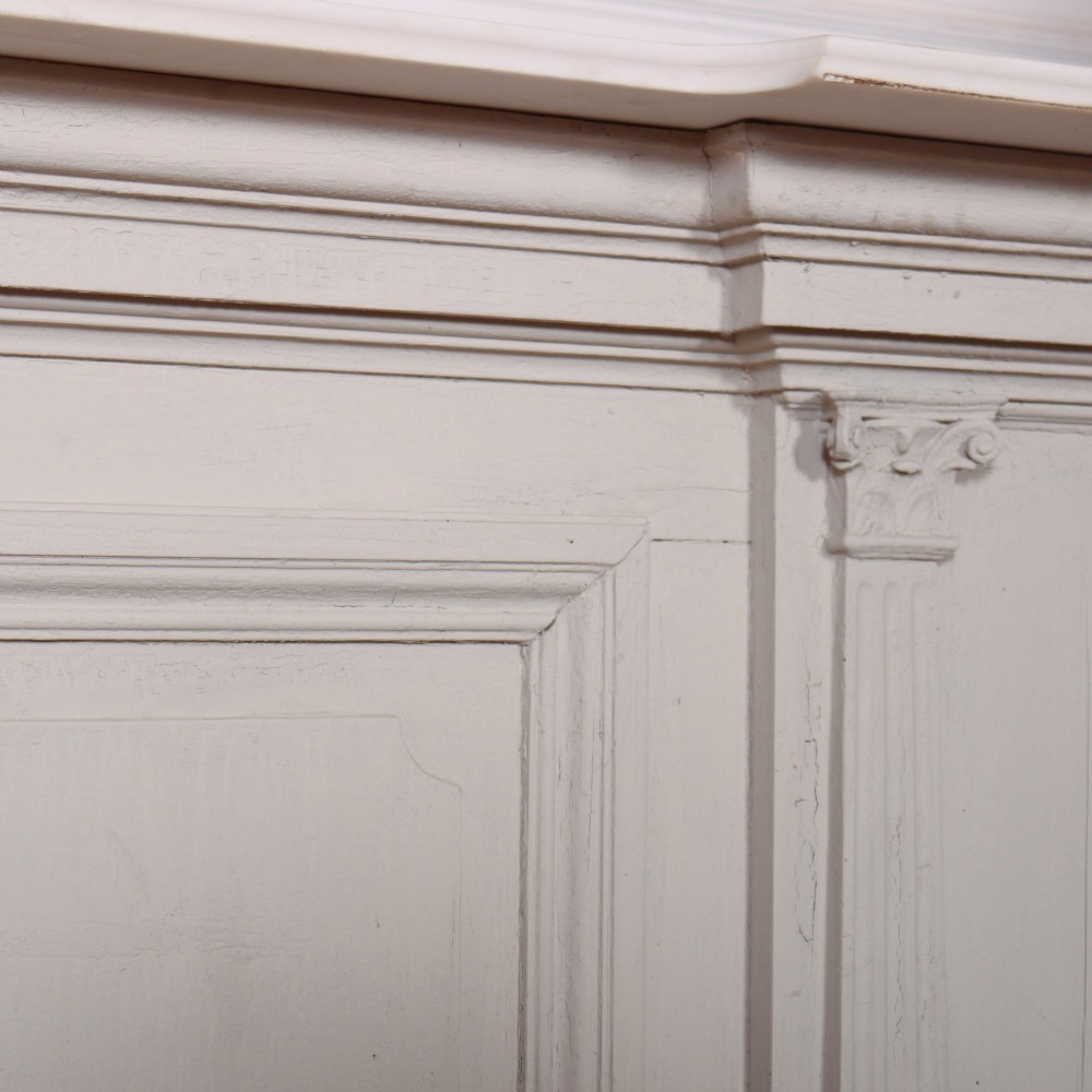 A long off-white painted timber shop counter featuring fluted Corinthian pilasters and recessed panel moulding along the front. View IX