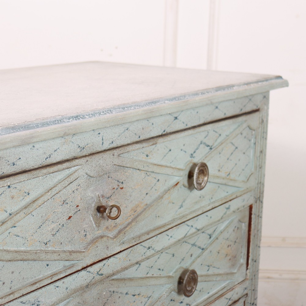 A pale blue painted Spanish commode with three drawers decorated with a distressed diamond lattice pattern and metallic ring pulls. View X
