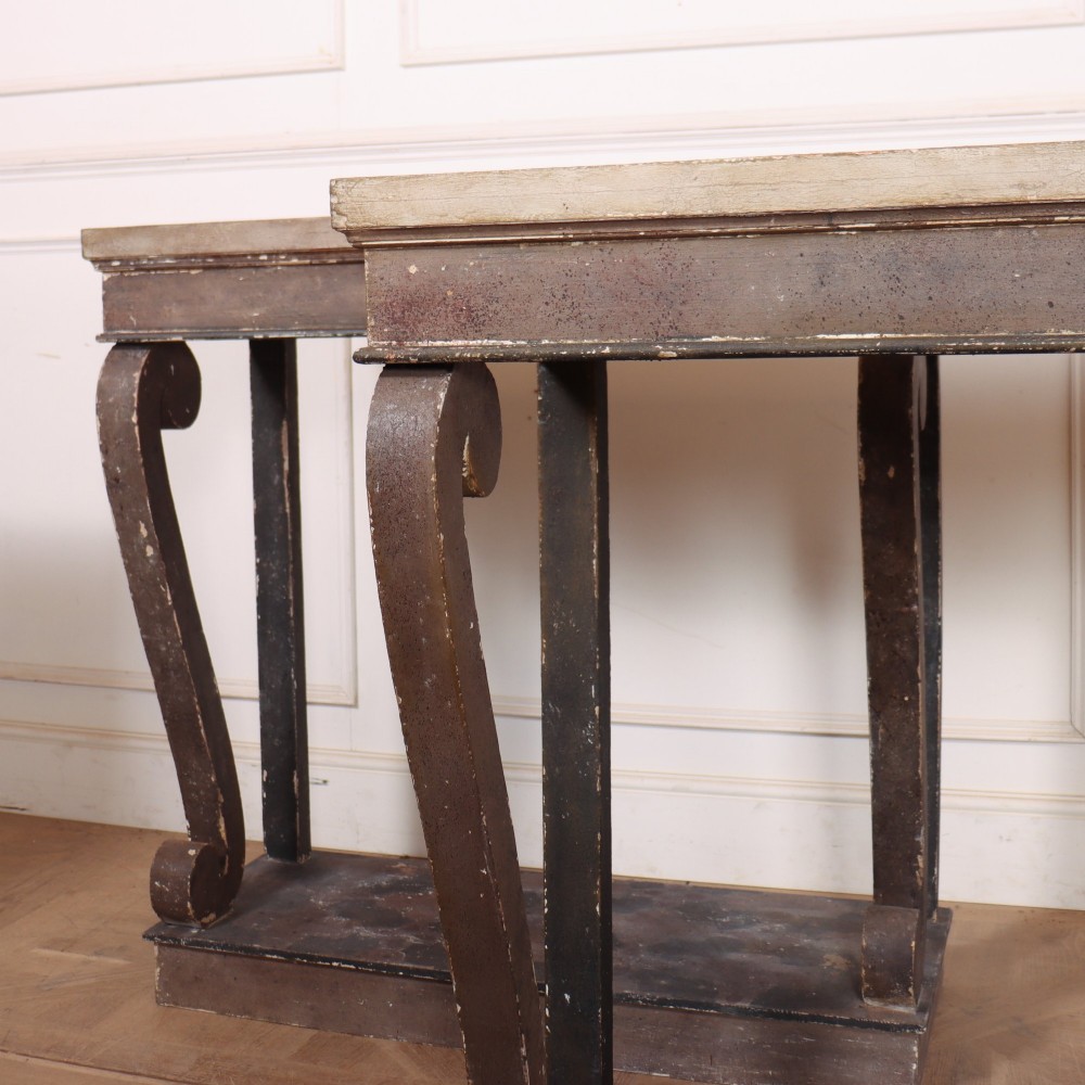 A pair of narrow Spanish painted wood console tables with curved upright supports, patterned top surfaces, and lower shelves. View V