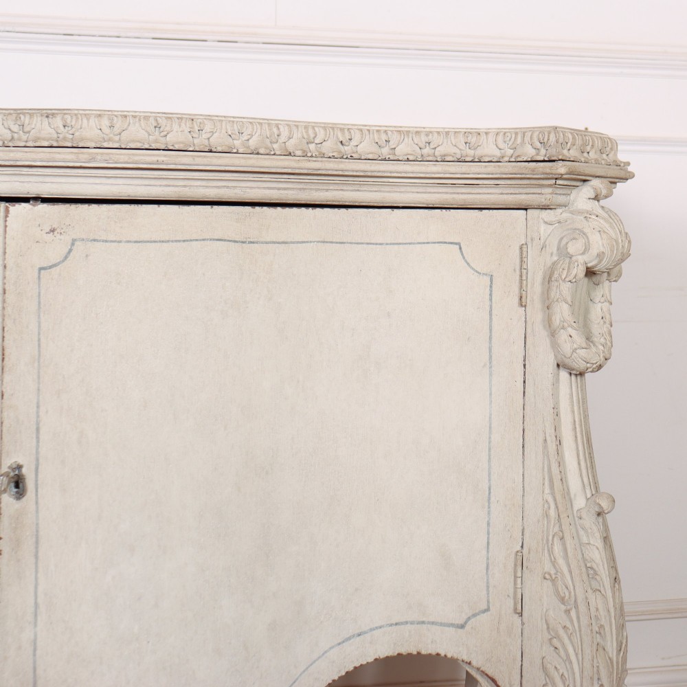 An off-white painted Italian Rococo side cabinet featuring carved acanthus leaf shoulders, a serpentine lower apron, double doors with painted blue trim, and prominent carved claw feet. View V