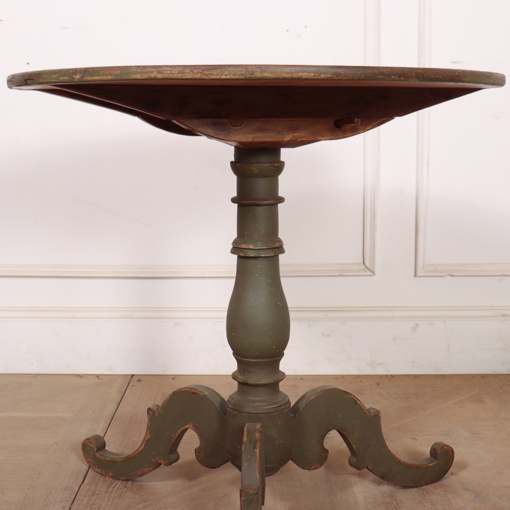 An antique Swedish painted wooden side table featuring a circular top, turned central pedestal, and scrolled tripod legs in a muted green finish. View III