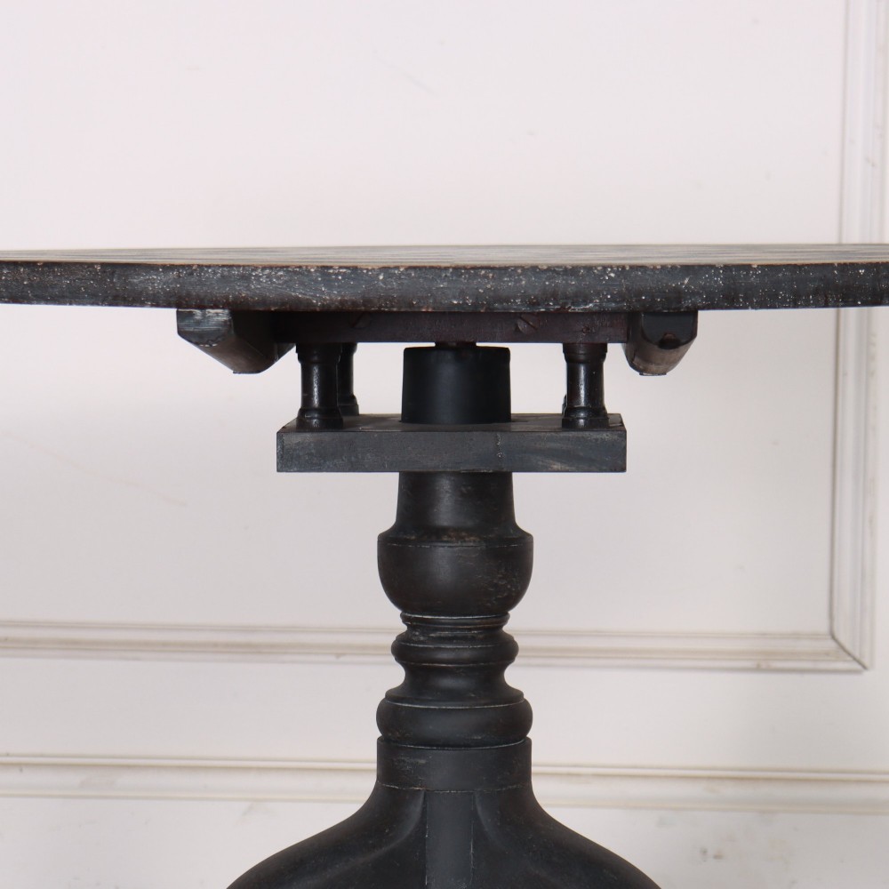 A circular tilt-top tripod table featuring a painted concentric checkerboard top in black and cream, supported by a dark three-legged base on castors. View VIII