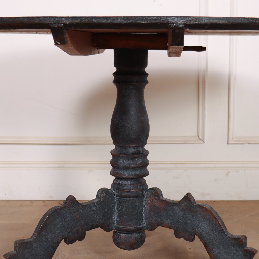An antique Swedish round supper table featuring a dark distress-painted top set on a turned baluster pedestal with shaped tripod legs. View IV