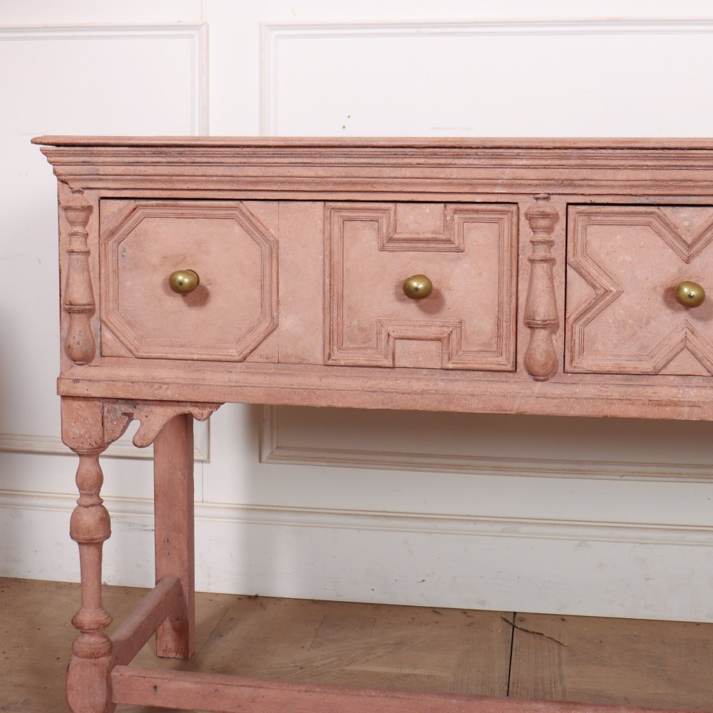 A long English painted dresser base featuring five geometric mouldings across the drawer fronts, brass knobs, turned legs, and a low connecting stretcher. View II