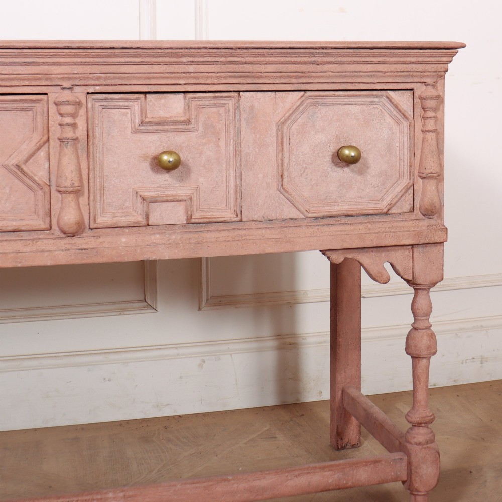 A long English painted dresser base featuring five geometric mouldings across the drawer fronts, brass knobs, turned legs, and a low connecting stretcher. View V