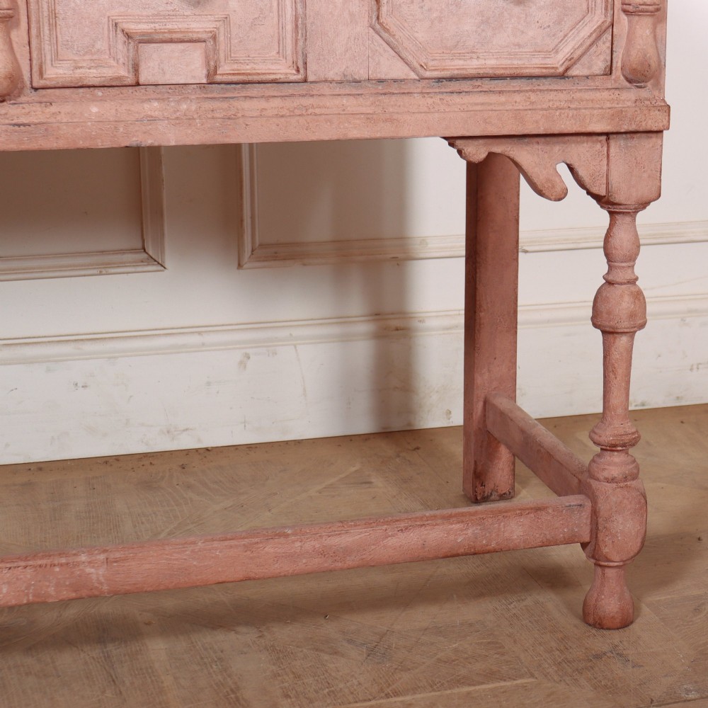 A long English painted dresser base featuring five geometric mouldings across the drawer fronts, brass knobs, turned legs, and a low connecting stretcher. View VI