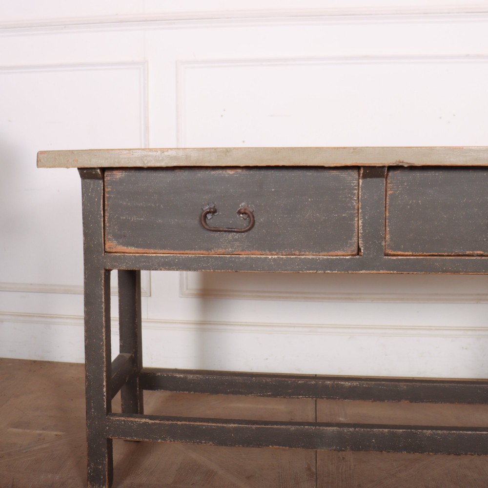 An antique English painted server table featuring a grey painted top over two dark grey drawers with metal drop handles and a low stretcher base. View II