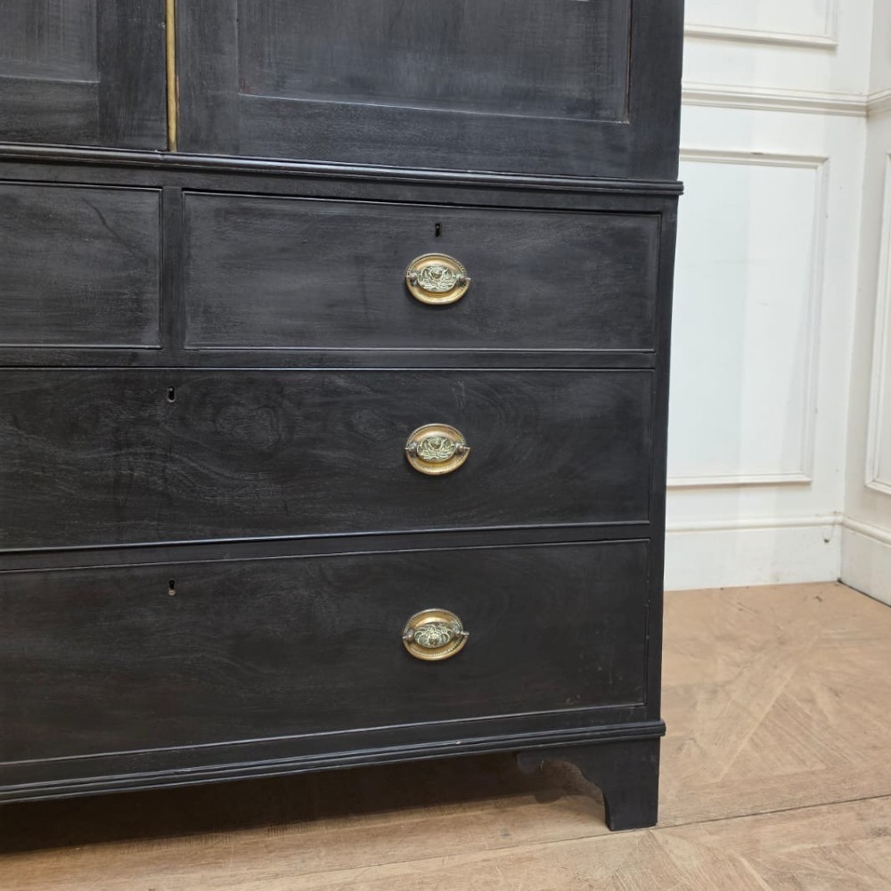 An ebonised black timber linen cupboard featuring two upper panelled doors above two short and two long drawers with brass drop handles. View V
