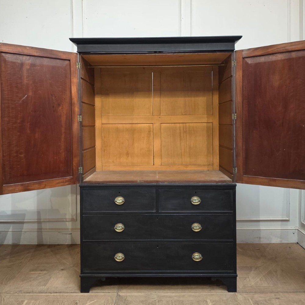 An ebonised black timber linen cupboard featuring two upper panelled doors above two short and two long drawers with brass drop handles. View VIII