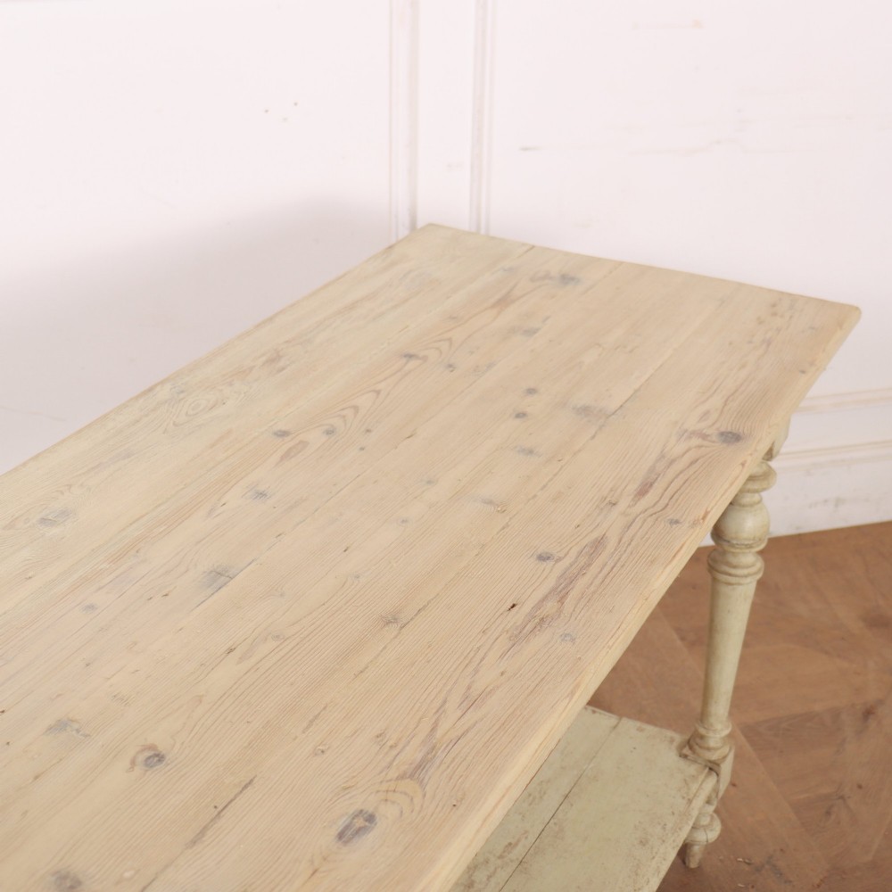 A long French painted drapers table featuring a natural pine top, a cream-painted base with turned legs, and a low open undershelf. View V