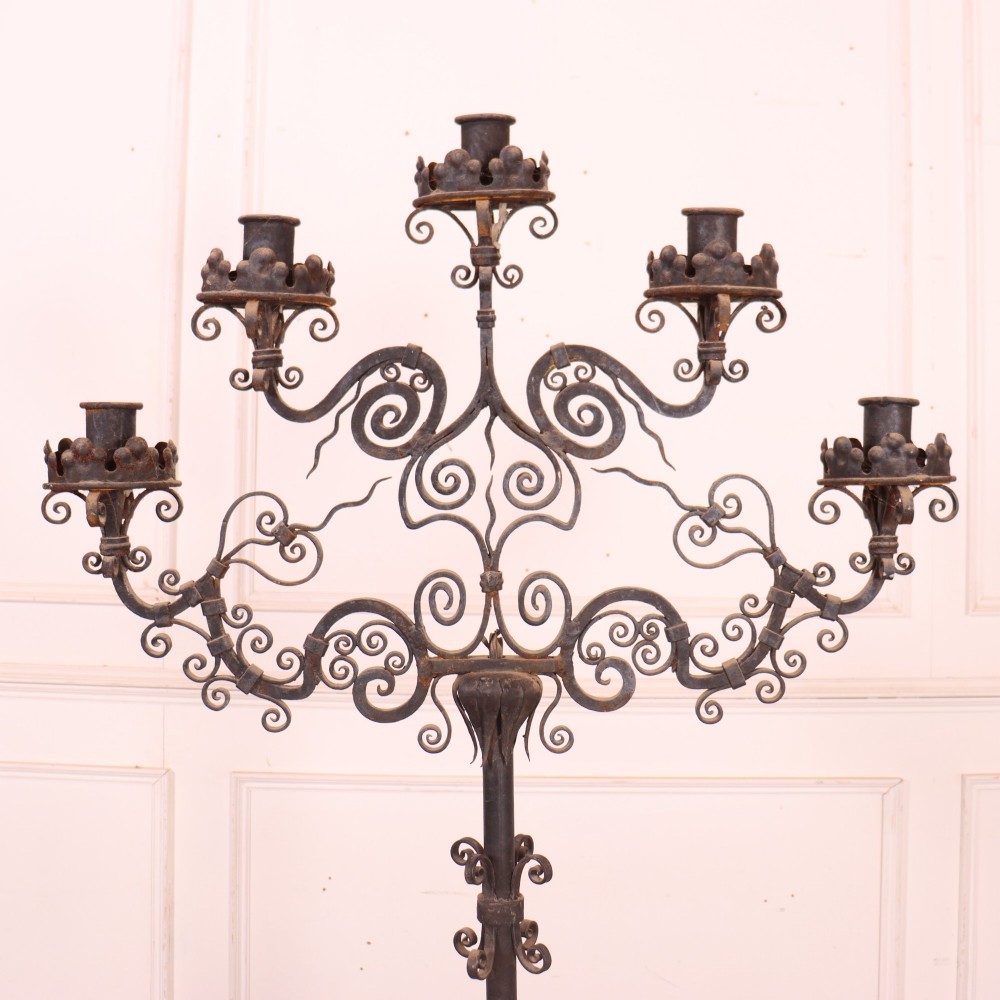 A tall dark wrought iron floor candelabra featuring scrollwork arms holding six candle sconces above a decorated stem and tripod scroll base. View II
