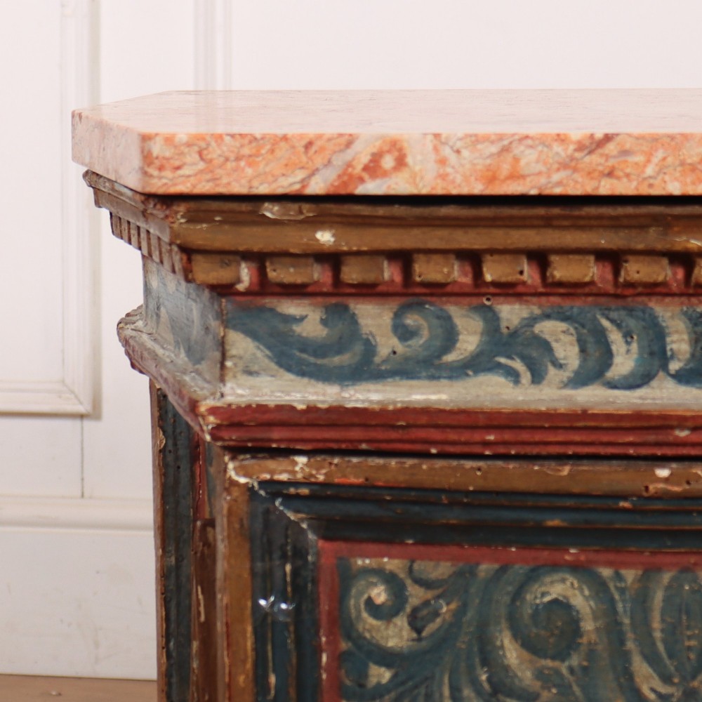 An antique Italian polychrome painted cabinet with a pink marble top, canted corners, and a central carved face mask panel. View III