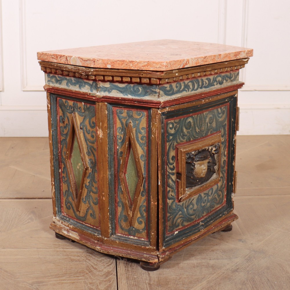 An antique Italian polychrome painted cabinet with a pink marble top, canted corners, and a central carved face mask panel. View VI