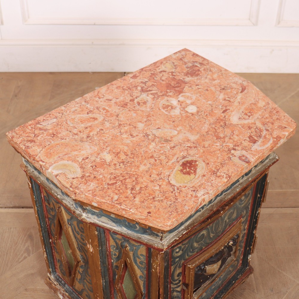 An antique Italian polychrome painted cabinet with a pink marble top, canted corners, and a central carved face mask panel. View IX