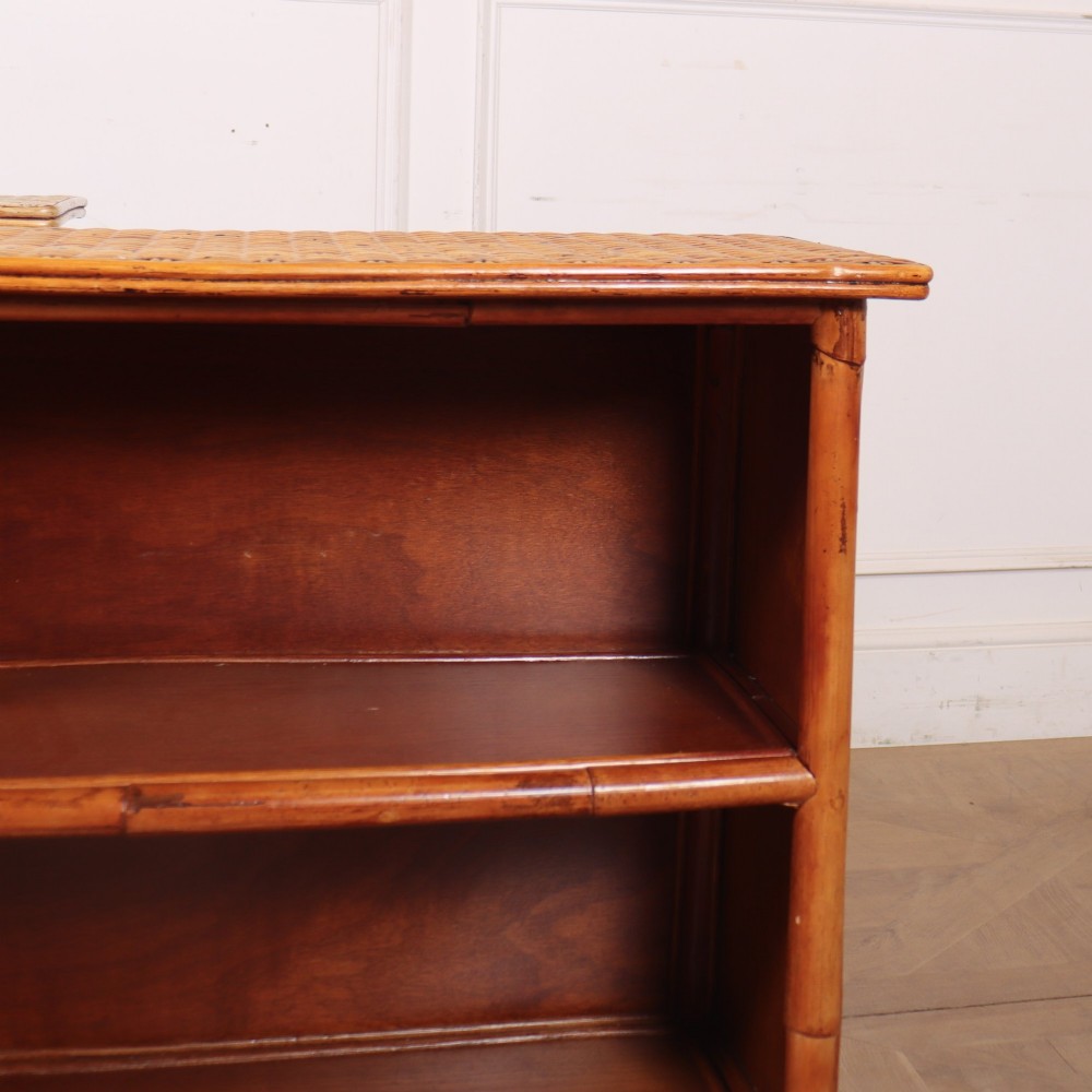 A pair of low vintage bamboo bookcases featuring woven cane tops and two open wooden shelves. View II