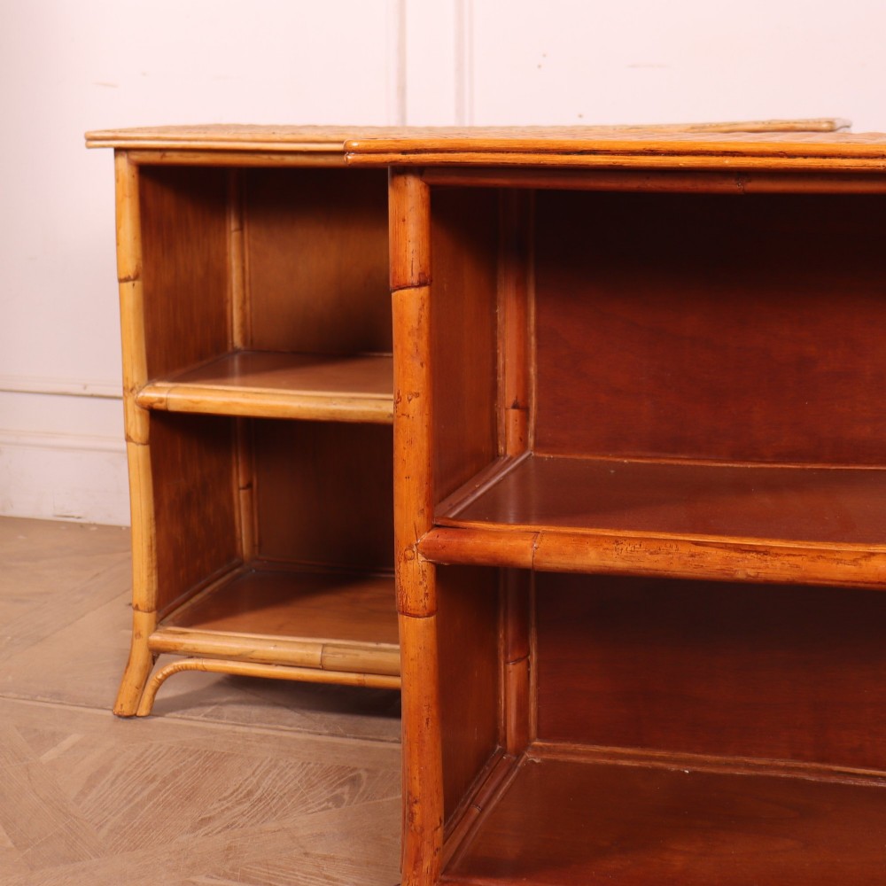 A pair of low vintage bamboo bookcases featuring woven cane tops and two open wooden shelves. View V
