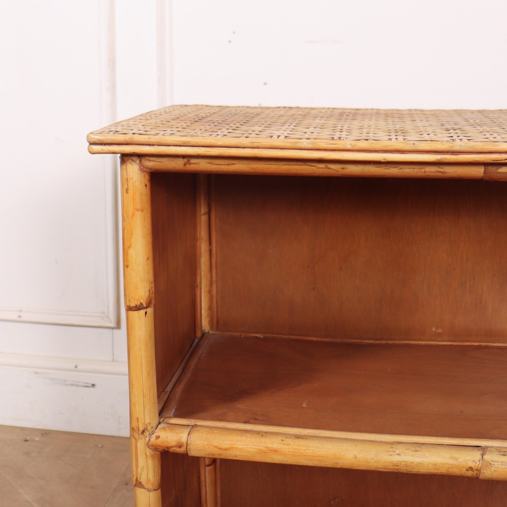 A pair of low vintage bamboo bookcases featuring woven cane tops and two open wooden shelves. View IX